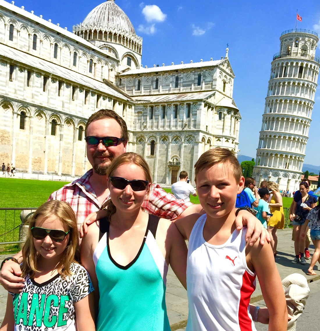 family posed in front of the leaning Tower f Pisa 